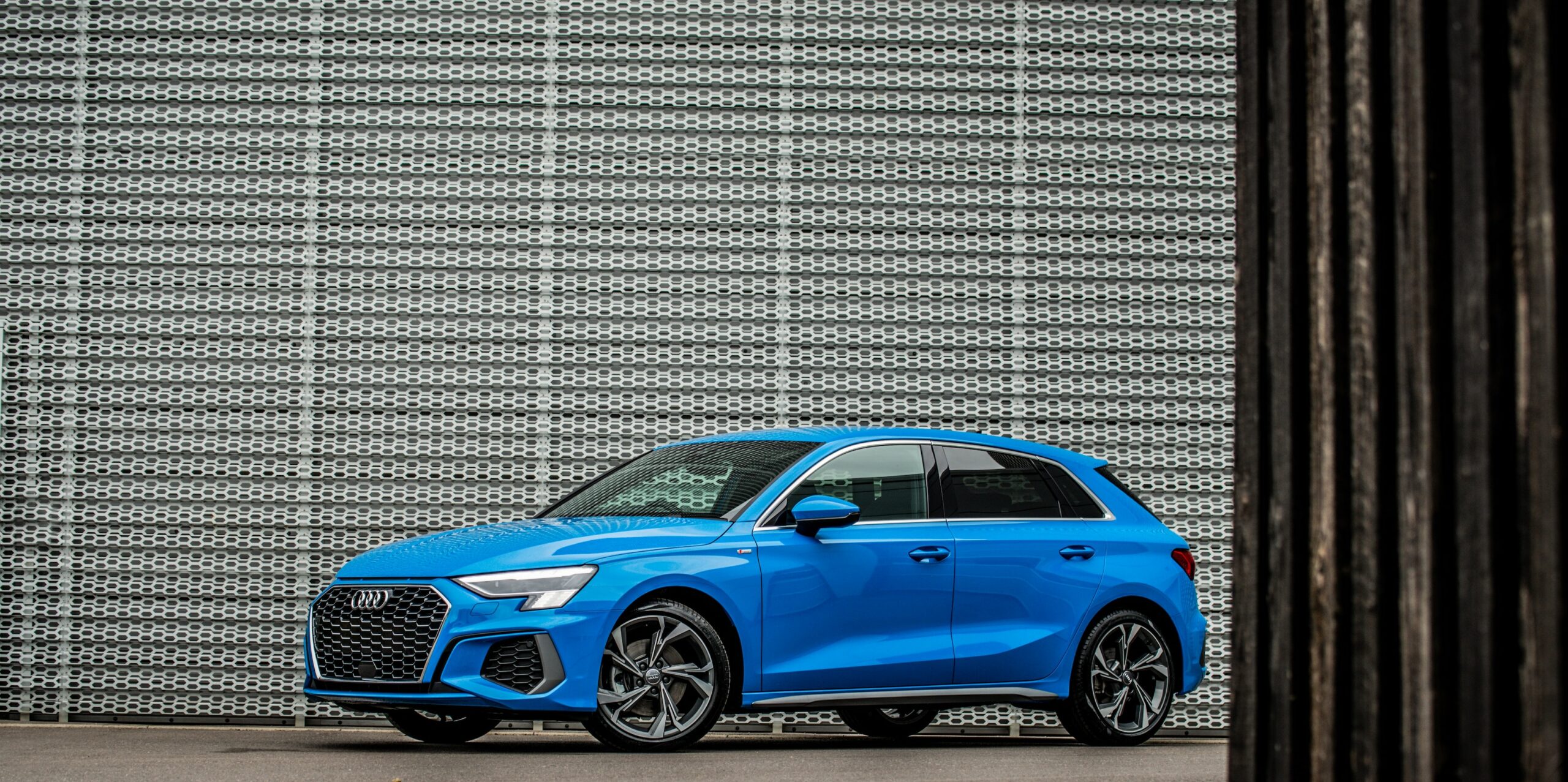 A blue Audi A3 with TFSI engine parked outside and Audi dealership