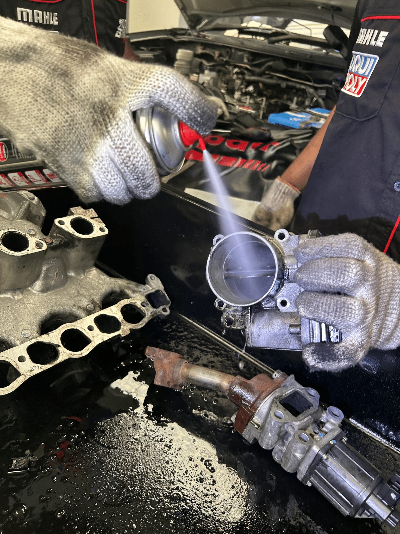 A bottle of EGR valve cleaner with a nozzle spraying onto the engine component