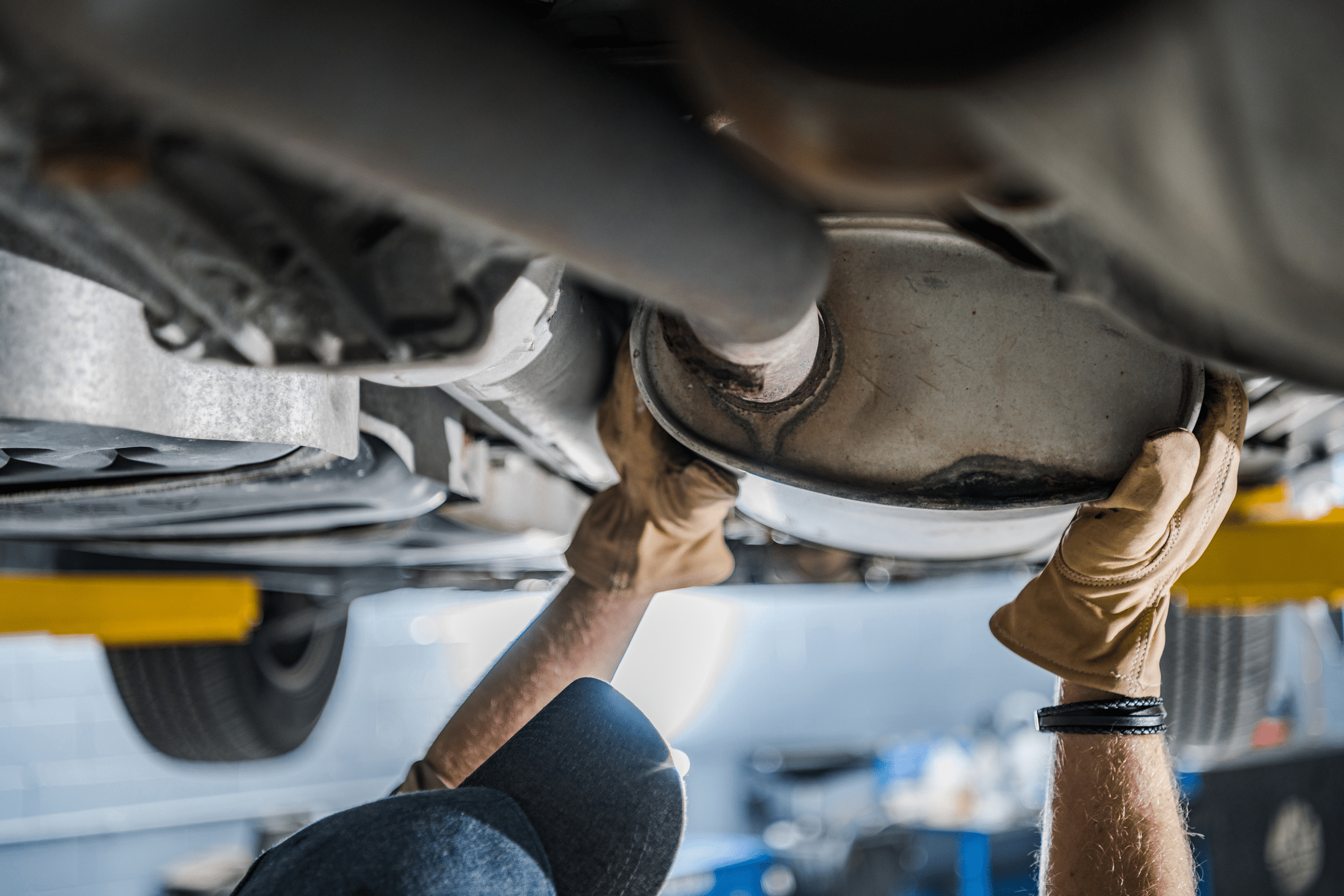 A mechanic inspecting the exhaust system and catalytic converter of a car