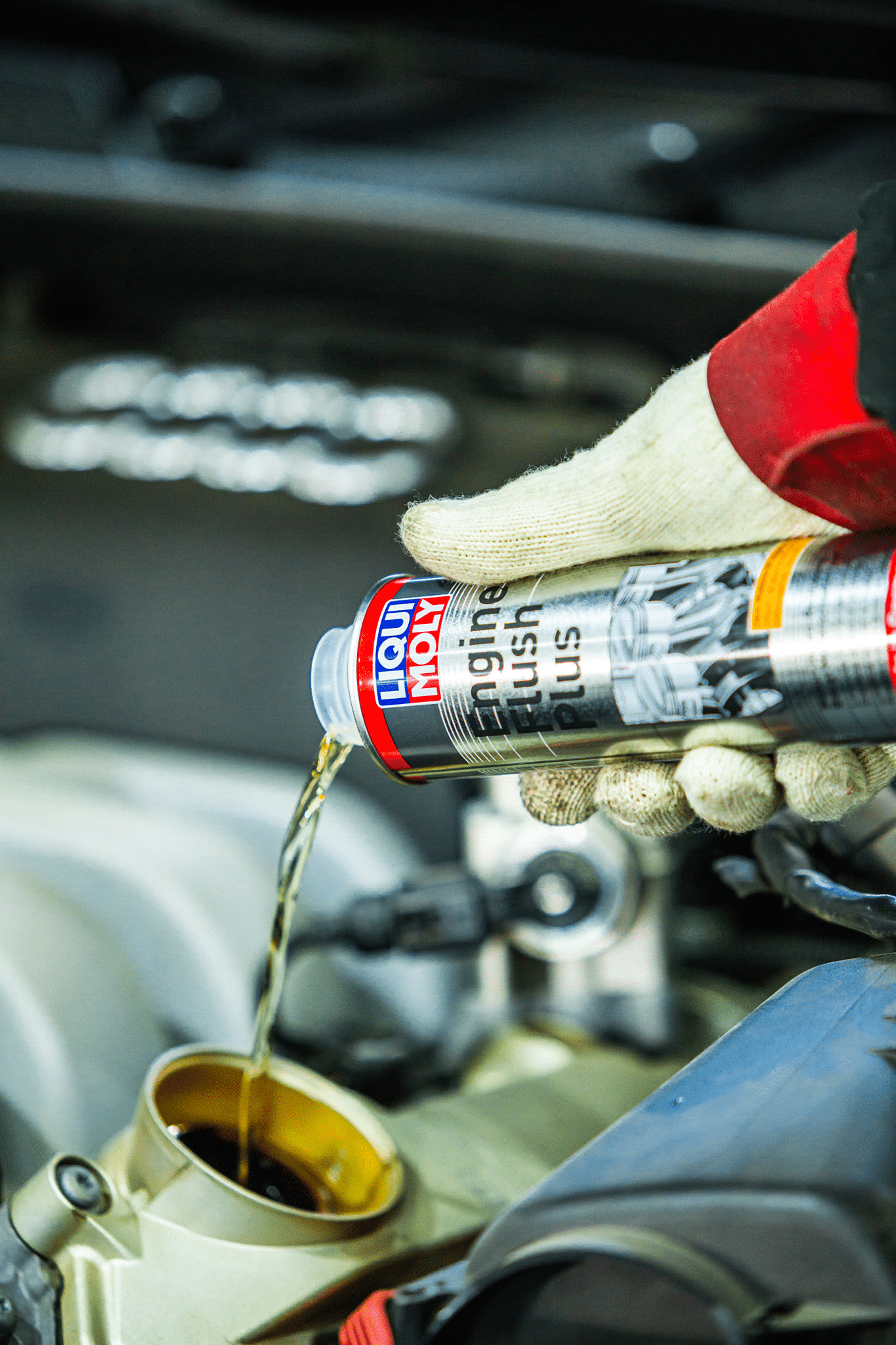 A person pouring engine oil into a car engine